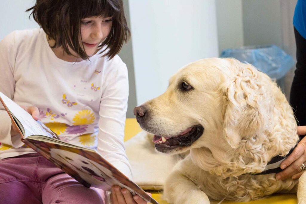 Cane che guarda un libro con una bambina