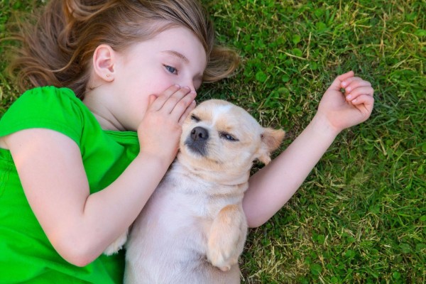 una bambina e un cane sono distesi sull'erba
