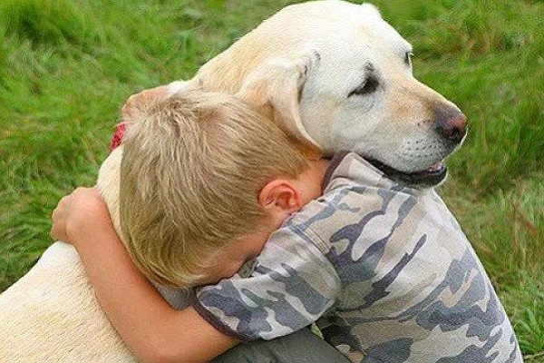 bambino biondo abbraccia cane