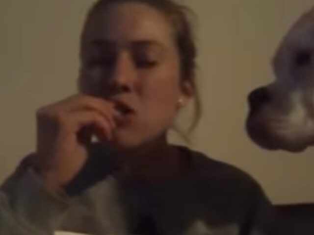 Donna prova a mangiare lo snack senza che il suo cane se ne accorga