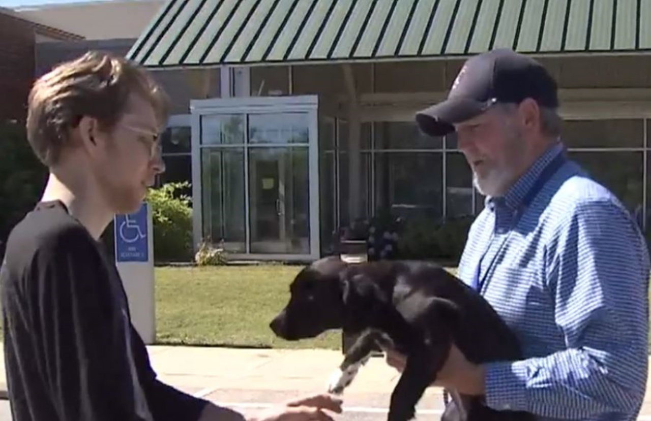 due uomini con una cagnolina dal mantello nero
