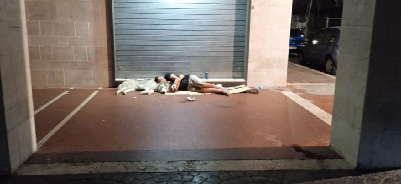Senzatetto dorme per terra con il cane