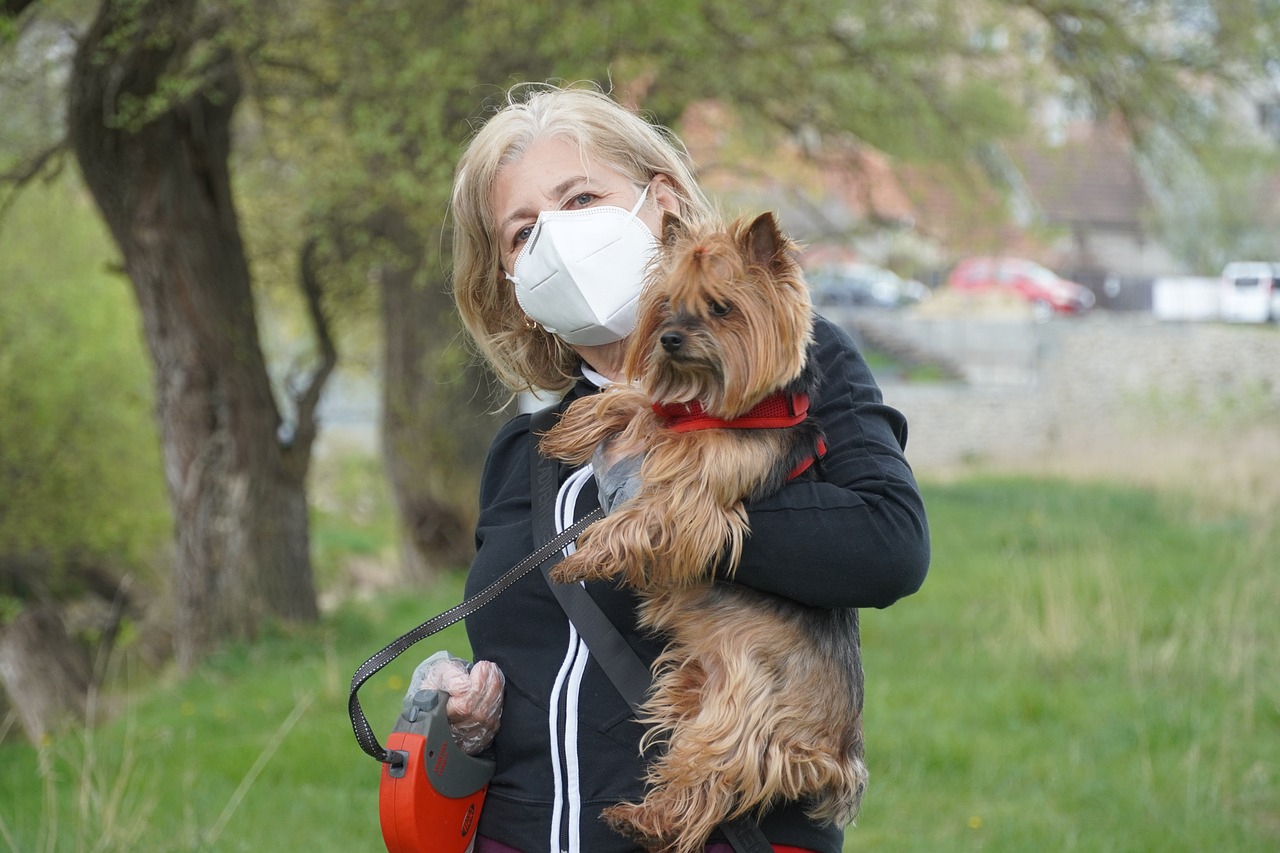 Donna con mascherina e cane in braccio