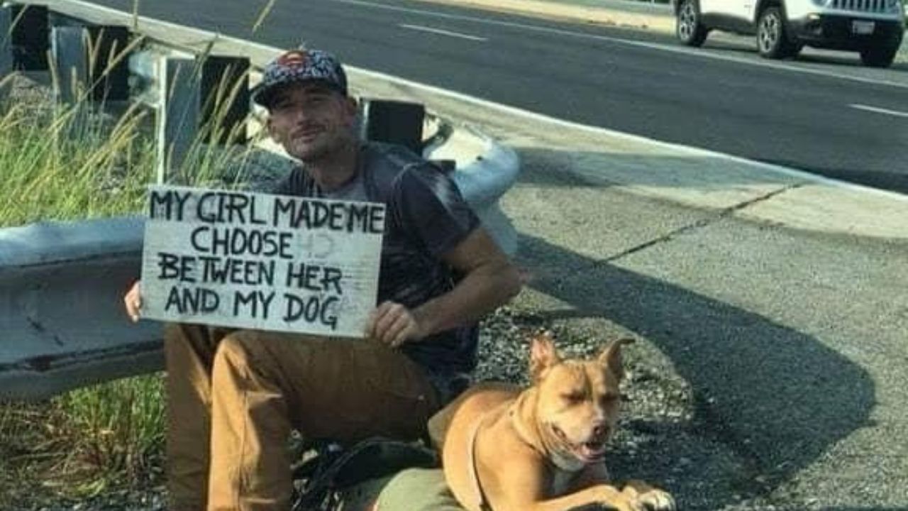 Uomo con cane tiene in mano un cartello